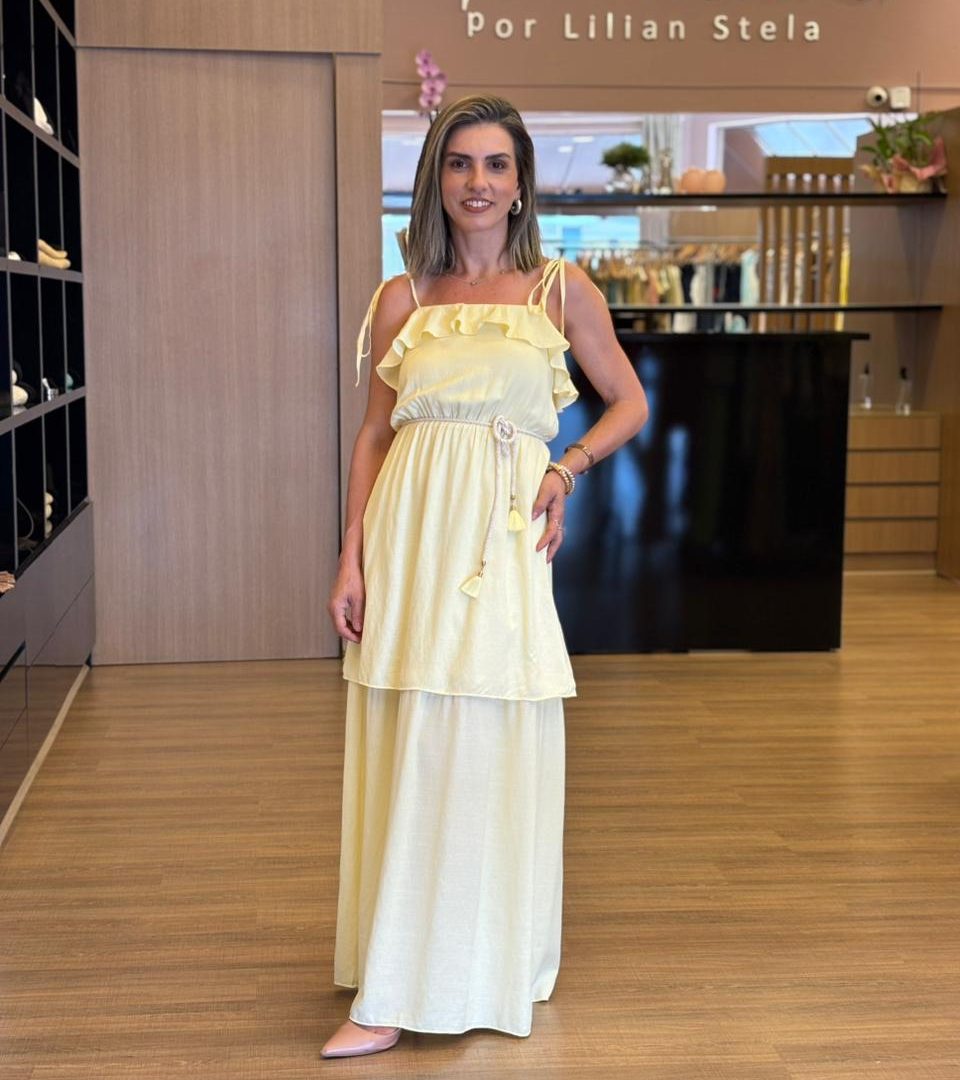 Vestido amarelo longo com babados e alças com amarração nos ombros.