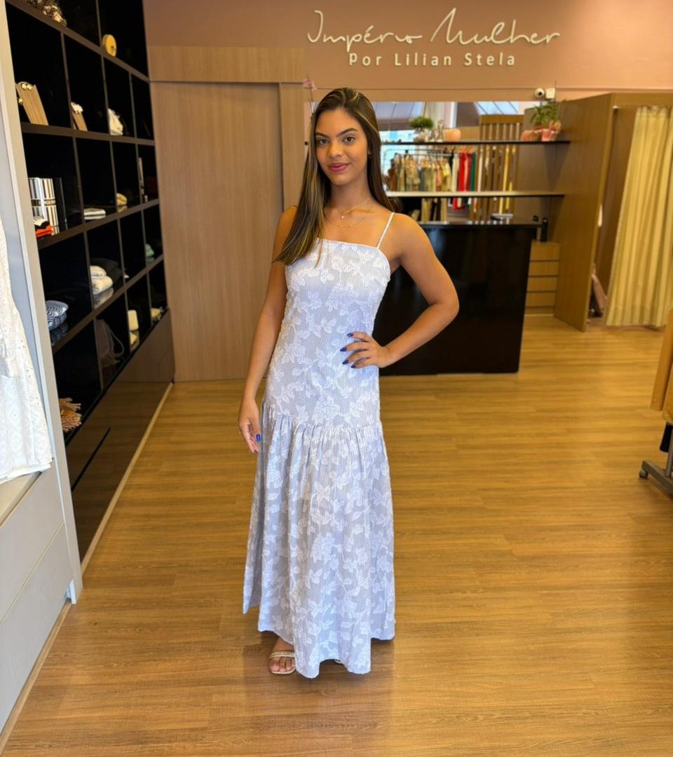 Modelo vestindo vestido longo com estampa floral em relevo, alças finas e saia fluida.