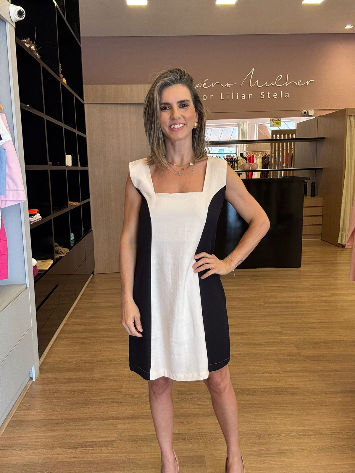 Modelo vestindo vestido curto bicolor feminino elegante com recortes laterais.