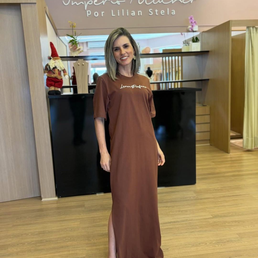 Modelo vestindo vestido super midi marrom de manga curta com modelagem reta e fenda lateral.