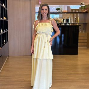 Vestido amarelo longo com babados e alças com amarração nos ombros.