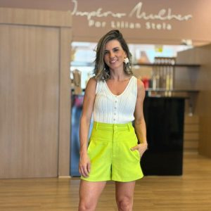 Modelo vestindo short verde lima de alfaiataria, cintura alta, com caimento estruturado e comprimento confortável.