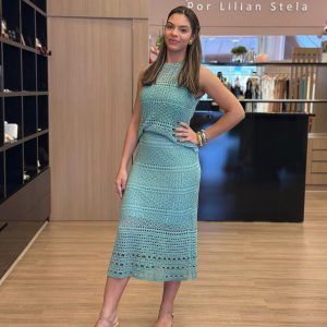 Modelo usando conjunto em tricot verde água, composto por blusa sem mangas com trama vazada, blusa interna por baixo e saia midi com caimento elegante.
