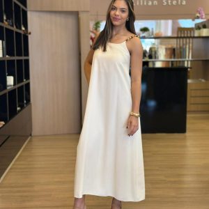 Modelo vestindo vestido midi off-white de alças finas com detalhe em corrente.