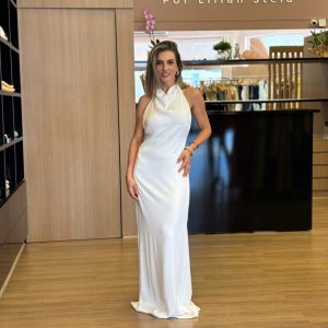 Vestido longo branco de frente única, com caimento fluido, costas abertas com amarração e modelagem elegante.