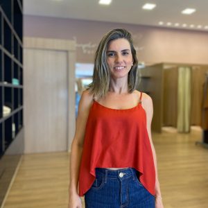 Modelo veste blusa vermelha de alças finas, com caimento solto e tecido leve.