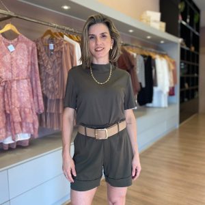 Modelo veste conjunto feminino verde militar com blusa de manga curta, short de alfaiataria com pregas e cinto largo bege.